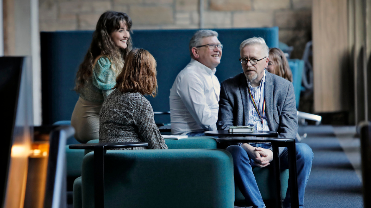 A small group of people sit on sofas in coversation