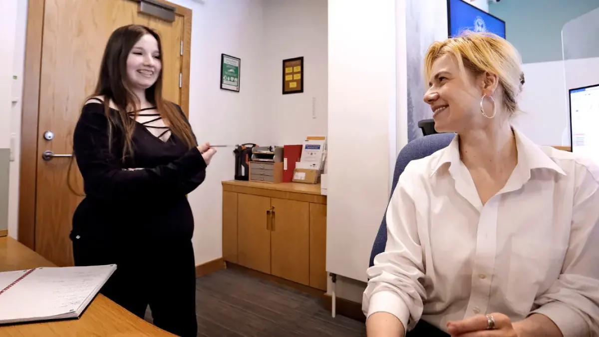 Two female staff members chat at reception
