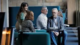 A small group of people sit on sofas in coversation