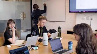 EI colleagues sit around a desk in lively discussion