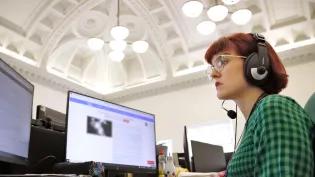A woman in a green dress looks at her computer screen