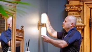 A member of the Estates maintenance team up a ladder fixing a light 