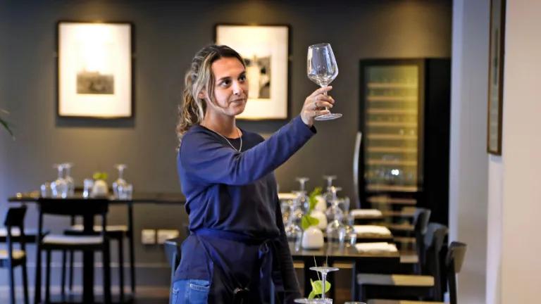 A young waiter inspects a glass in a restaurant