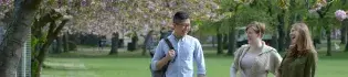 A group of three students in the Meadows, in front of a blossom tree