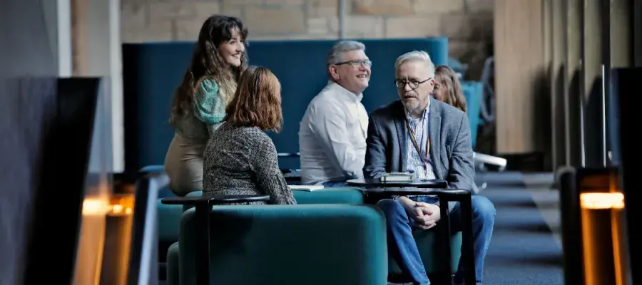 A small group of people sit on sofas in coversation