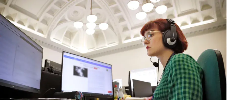A woman in a green dress looks at her computer screen