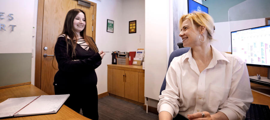 Two female staff members chat at reception