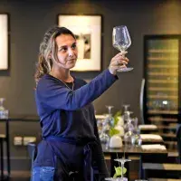 A young waiter inspects a glass in a restaurant
