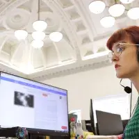 A woman in a green dress looks at her computer screen