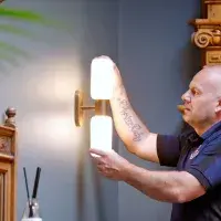 A member of the Estates maintenance team up a ladder fixing a light 