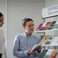 A group of EUP colleagues stand in conversation around a stack of books
