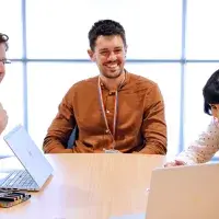 Five colleagues from HR look at a laptop smiling 