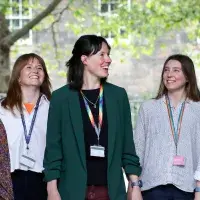 A group of five female colleagues walk and talk outside