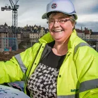 An Estates deputy director holds out plans while wearing a hi-vis jacket