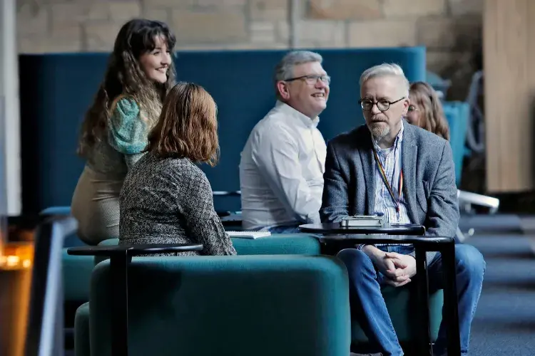 A small group of people sit on sofas in coversation