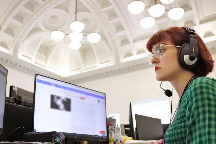 A woman in a green dress looks at her computer screen